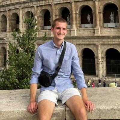 In his downtime, an undergraduate student sits in from of the colosseum.